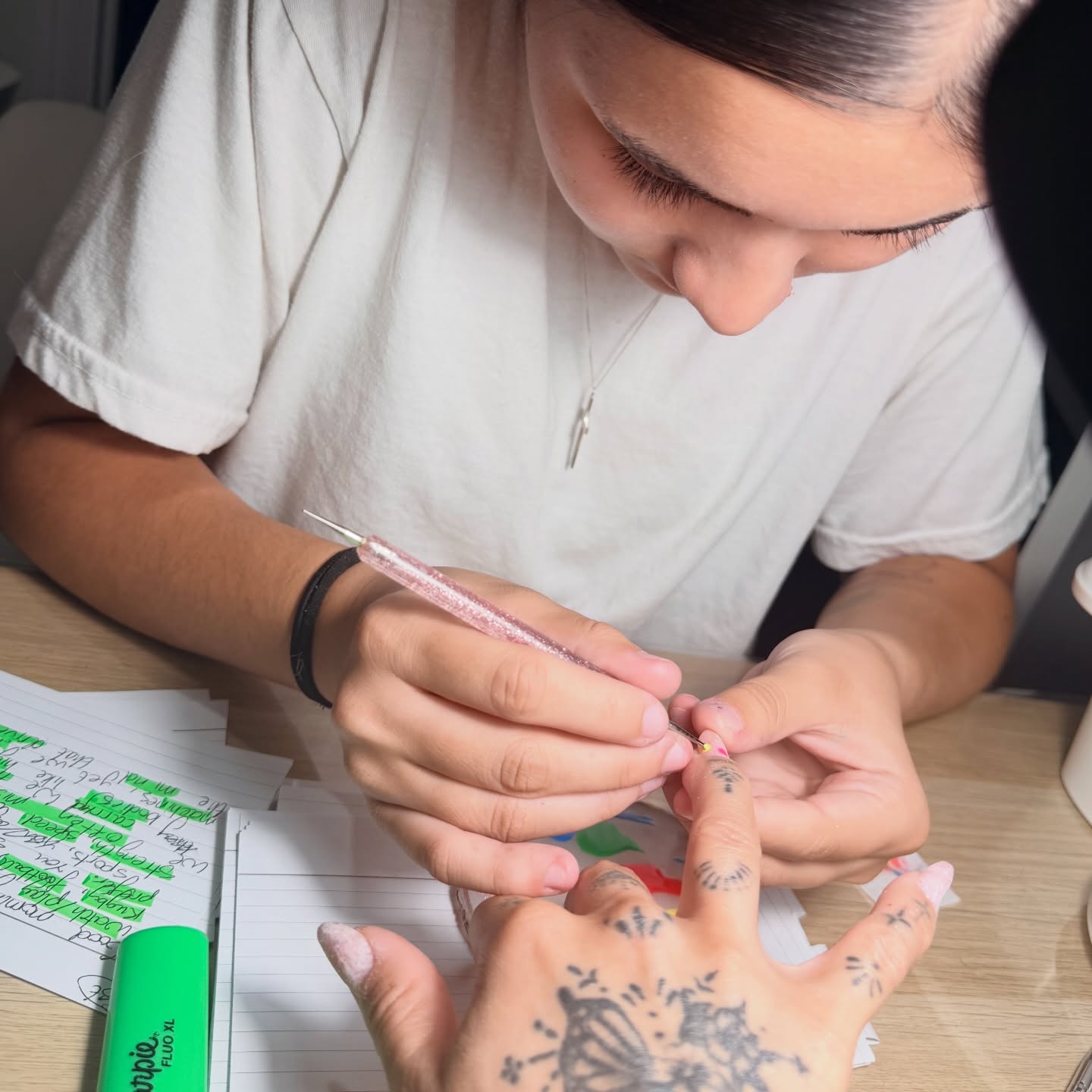 Nail technician applying glitter polish to a client's nails