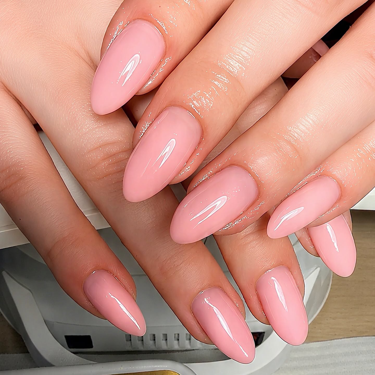 Almond shaped pink manicure with a glossy finish and sparkle accents
